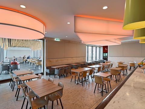 Barbereich im Café Leopold mit langen Holztresen, Barhockern und moderner Deckenbeleuchtung