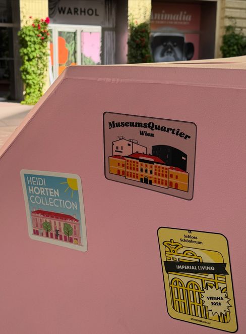 Close-up of a pink Enzi seating sculpture featuring stickers from MuseumsQuartier Wien, Heidi Horten Collection, and Schönbrunn Palace.