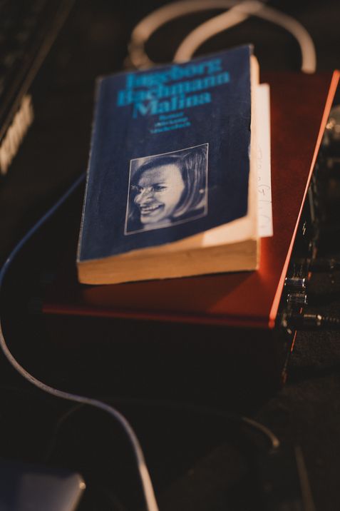 Ein auf einem roten Buch liegendes, abgenutztes blaues Buch mit einem Schwarz-weiß-Foto eines lächelnden Mädchengesichts auf dem Einband.