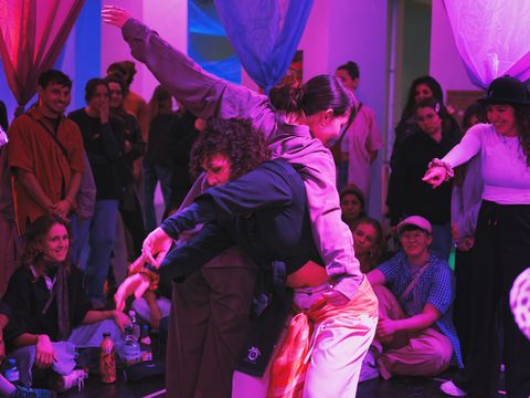 Two people are dancing surrounded by people watching.