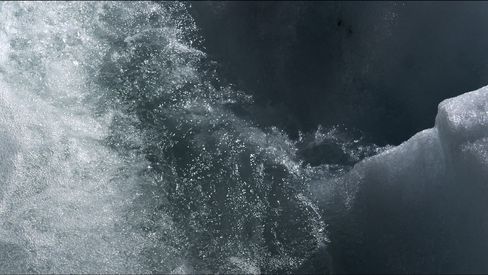 Nahaufnahme von Wasser, das über eine eisige Oberfläche spritzt.