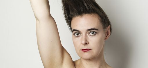 Oberkörper einer unbekannten Person, die mit einer Hand ihr langes Haar nach oben zieht