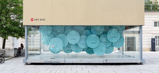 MQ Art Box in MuseumsQuartier Vienna featuring the installation “EMOTION” by Herbert de Colle, composed of numerous turquoise floating face-like forms.