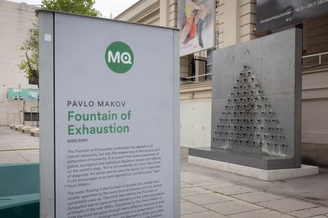 Information panel for the installation “Fountain of Exhaustion” by Pavlo Makov at MuseumsQuartier Vienna, with the sculptural fountain beside it.