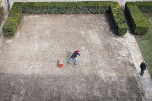 Aerial view of two people on a sandy surface, one person pulling a roller behind them.