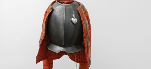 The image features a unique and creative sculpture of a person wearing a suit and boxing gloves. The sculpture is made of metal and is hanging from the ceiling.