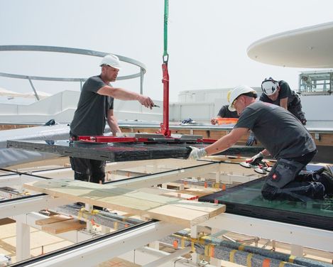 Personen mit Schutzhelm setzen ein Glas in ein Dach ein