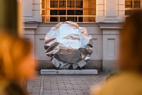 Large round silver reflective inflatable object in front of a historic building with columns