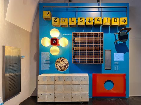 Blue wall with several objects fixed to it. E.g., an armchair or four white lights.