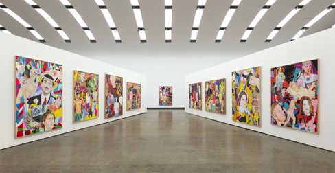 Multiple colorful paintings with portraits and abstract patterns hang on the white walls of a large, modern exhibition hall.