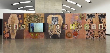 An art exhibition featuring five colorful collages composed of many small portraits and figures, hanging in front of a large-format, abstract black-and-white painting.