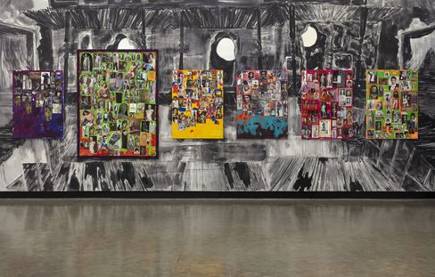 An art exhibition featuring five colorful collages composed of many small portraits and figures, hanging in front of a large-format, abstract black-and-white painting.