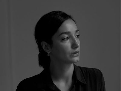 A black-and-white portrait of a woman wearing a dark blouse, looking to the right.