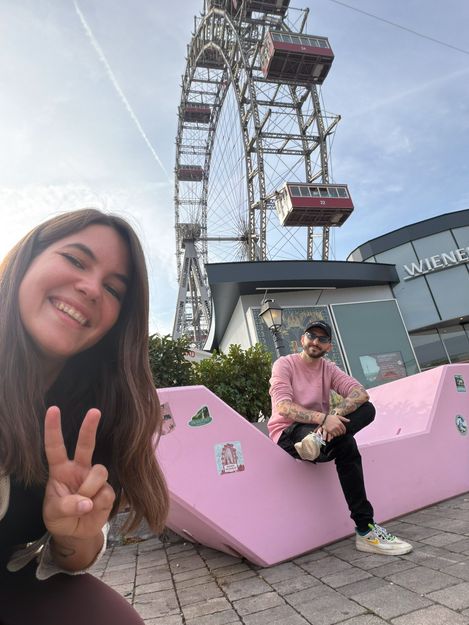 Zwei Personen posieren mit einem rosa Enzi vor dem Wiener Riesenrad im Wiener Prater.