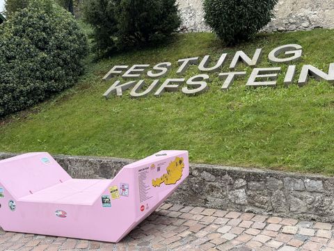 Rosa MQ-Möbel vor der Festung Kufstein, im Hintergrund der Schriftzug „Festung Kufstein“ auf einem grünen Hang.