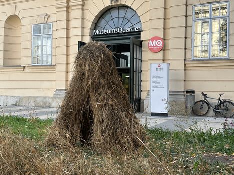 A haystack shaped like the letter “A” is in the foreground. An MQ entrance can be seen in the background.