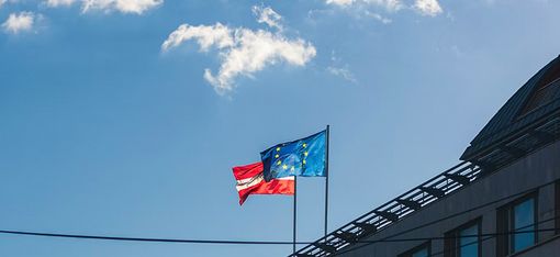 Two flags are flying from the roof of a house: the Austrian flag and the European flag.