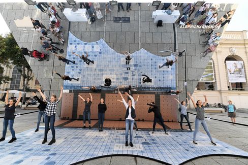 Einige Menschen tanzen im Innenhof des MQ unter einem Spiegel mit der Aufschrift: Elbphilharmonie Hamburg.