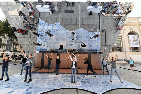 Einige Menschen tanzen im Innenhof des MQ unter einem Spiegel mit der Aufschrift: Elbphilharmonie Hamburg.