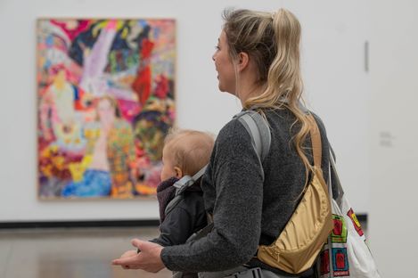 Eine Person mit Baby betrachtet ein Kunstwerk.