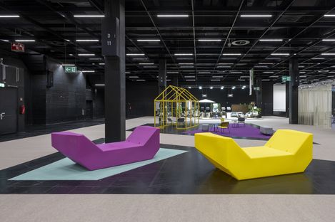 Zwei Enzos in Gelb und Violett stehen in einer großen Messehalle und strukturieren den offenen Raum als Sitz- und Aufenthaltsbereich.