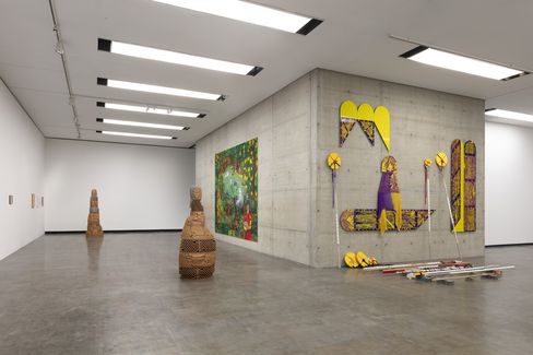 Ein Ausstellungsraum mit mehreren Skulpturen und einem großen Gemälde.