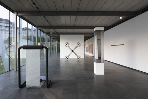 In einem länglichen Ausstellungsraum stehen mehrere Skulpturen aus Metall und weiteren Materialien.