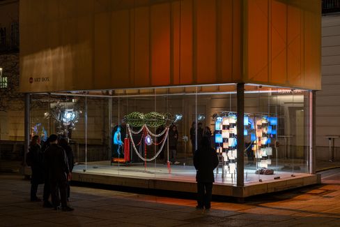 Glass display case with modern art installation surrounded by several people at night in MuseumsQuartier Vienna