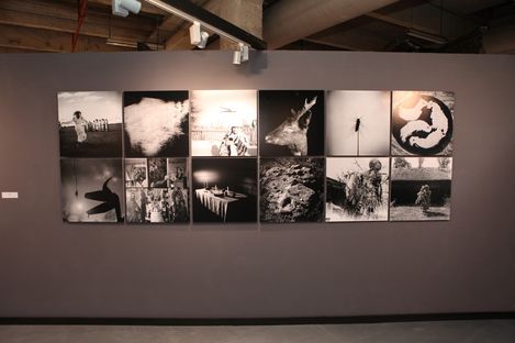 Wall with twelve black-and-white photographs arranged in two rows, including a jumping person, a deer head, and a lunar landscape.