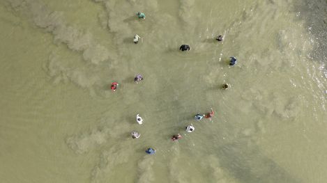 Aerial view of several people standing in water arranged in a loose circle
