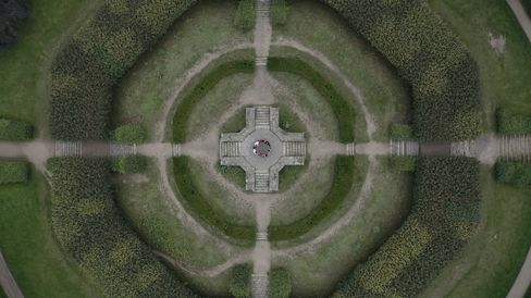 Aerial view of a symmetrical circular garden with a central stone monument and four intersecting paths