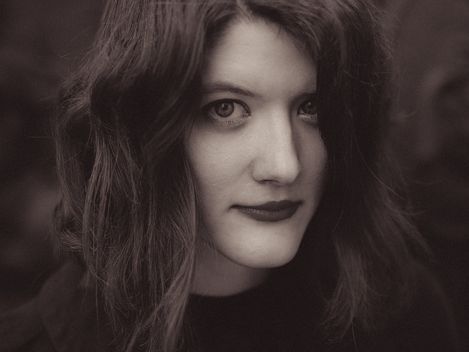 Person with shoulder-length wavy hair against a dark background.