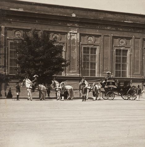 Altes Foto einer Pferdekutsche vor einem hohen, alten Gebäude.