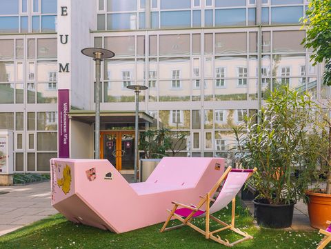 Pink Enzi in front of the Möbelmuseum Wien in the MuseumsQuartier, surrounded by plants and deck chairs.
