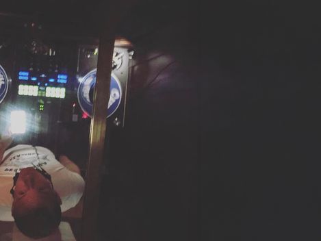 Person von oben in einem dunklen Raum vor einem DJ-Pult mit beleuchteten Plattenspielern und Mischpult.