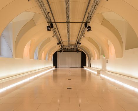 Großer Veranstaltungsraum Arena21 im MuseumsQuartier Wien mit gewölbter Decke und einer Leinwand am Ende des Raums.