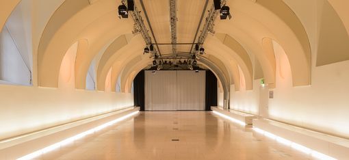 Großer Veranstaltungsraum Arena21 im MuseumsQuartier Wien mit gewölbter Decke und einer Leinwand am Ende des Raums.