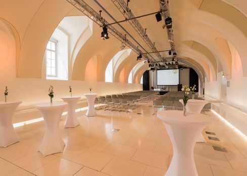 Large event space Arena21 at MuseumsQuartier Vienna with vaulted ceiling and a screen at the far end.