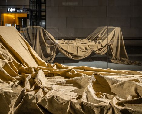 Installation “ENZA” in the MQ Art Box at night, showing dramatically lit folded fabric behind glass.