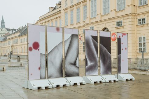 Back view of the installation showing large-scale, abstracted black-and-white body fragments across multiple panels in an outdoor setting with historic architecture.