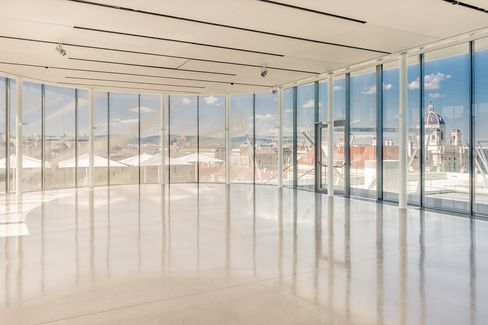 Großer, leerer Veranstaltungsraum mit bodentiefen Fenstern und Blick auf die Dächer von Wien, darunter eine Kuppel und historische Gebäude.