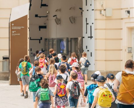 Eine Gruppe an jungen Kindern geht geführt von ihren Aufsichtspersonen durch die Innenhöfe des MQ.