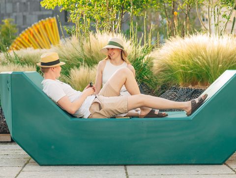 Zwei Personen sitzen auf einem grünen Enzi, umgeben von bepflanzten Inseln im MuseumsQuartier