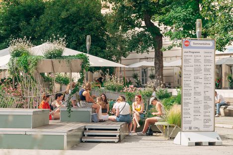 Viele junge Leute sitzen auf der MQ-Sommerbühne und unterhalten sich.