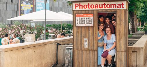 Photo booth in a public space with several people posing together for a picture.
