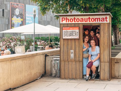 Photo booth in a public space with several people posing together for a picture.