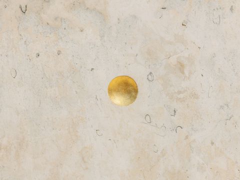 Goldener Punkt auf beigem, marmoriertem Hintergrund.