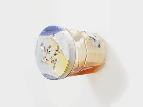 A sculpture of an oversized honey jar by Magali Reus, installed horizontally on the wall.