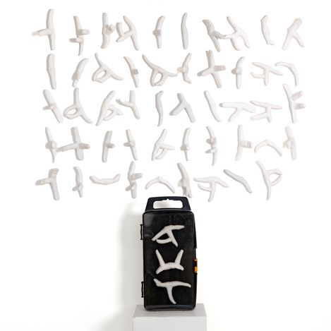 Black rectangular box with white abstract figures in various poses arranged above and on it.