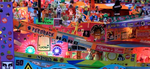 Bunte, detailreiche Installation mit zahlreichen kleinen Figuren, Aufklebern und Leuchtdioden auf mehreren Ebenen